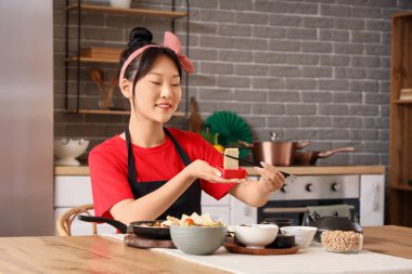Genç Asyalı kadın mutfakta soslu lezzetli tofu yiyor.