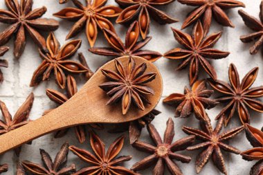 Wooden spoon with anise stars on white tile background