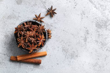 Anason yıldızları ve gri arka planda tarçınlı kase