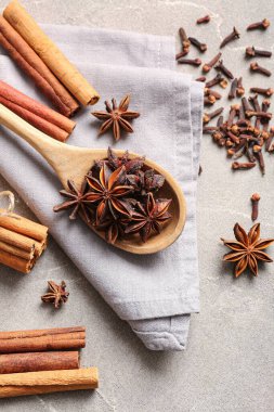 Anason yıldızlı ahşap kaşık, gri arkaplanda tarçın ve karanfil.