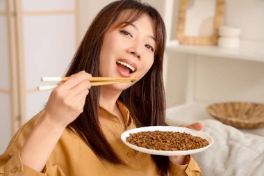 Yemek çubuklarıyla evde kızarmış böcek yiyen genç Asyalı kadın, yakın plan.