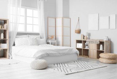 Tablolar, raf üniteleri ve katlanan ekranla aydınlık yatak odasının içi