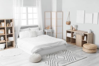 Tablolar, raf üniteleri ve katlanan ekranla aydınlık yatak odasının içi