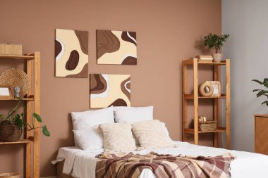 Tabloları, yatağı ve raf üniteleri olan şık bir yatak odası.