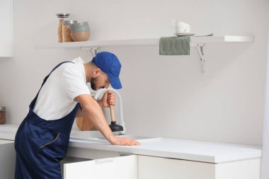 Lavabo pompalı erkek tesisatçı mutfağı temizliyor.