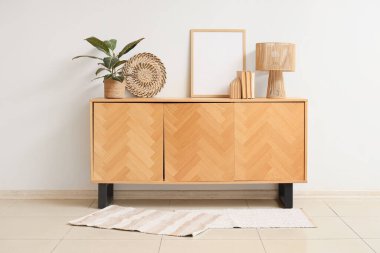 Kitaplı boş çerçeve, lamba ve bitki odasındaki ışık duvarının yanındaki ahşap klozette.