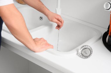 Mutfakta kablo temizleme borusu olan erkek tesisatçı, yakın plan.