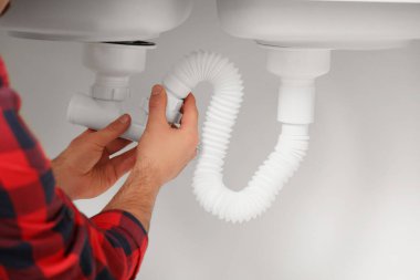 Erkek tesisatçı mutfaktaki lavabo borusunu tamir ediyor.