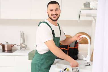 Erkek tesisatçı mutfakta tıkanmış boruyu temizliyor.