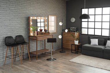 Masası, lambası ve kanepesi olan bir kuaför salonu.