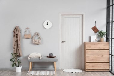 Koridorun içinde şık çantalar, palto ve yumuşak banklar var.