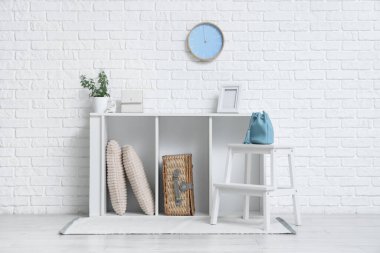 Odanın içinde şık çantalar, raf ünitesi ve tabure var.