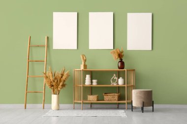 Raflar, merdiven ve boş posterler yeşil duvarda.