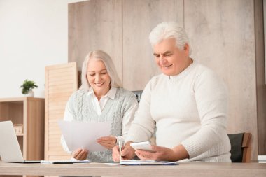 Mutfaktaki masada faturaları hesaplayan yaşlı çift.