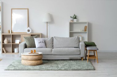 Oturma odasının içinde kanepe, raf üniteleri ve masada Türk çayı.