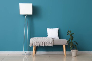 Yumuşak banklı şık lamba ve mavi duvarın yanında bitki.