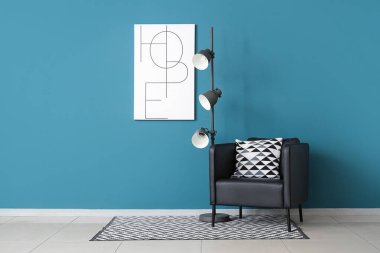 Koltuklu siyah lamba ve mavi duvarlı afiş.