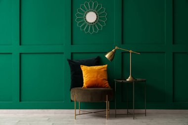 Yastıklı puf ve lamba yeşil duvarın yanındaki odada.
