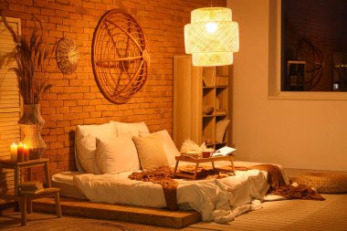 Yatak odasının içi kitaplık ve geceleri parlayan lambayla dolu.