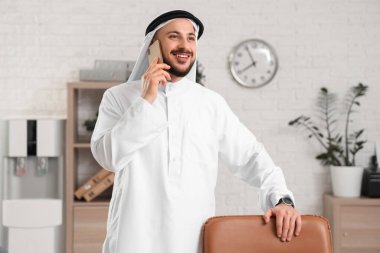 Arab businessman talking by mobile phone in office clipart