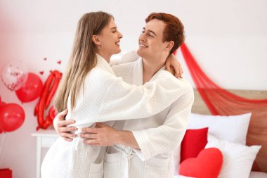 Young couple hugging in bedroom on Valentine's Day