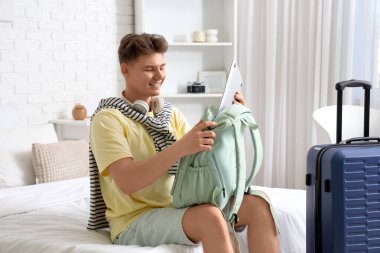 Erkek turist otel odasında sırt çantasından laptop alıyor.