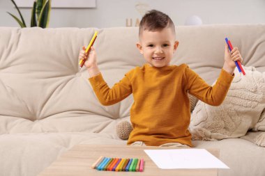 Evdeki masada keçeli kalemlerle çizen sevimli küçük çocuk.