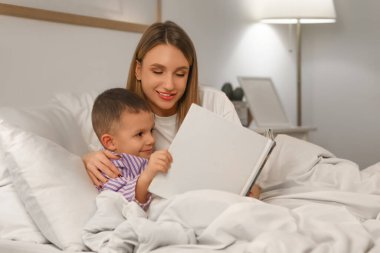 Anne ve küçük oğlu gece yatak odasında masal okuyorlar.