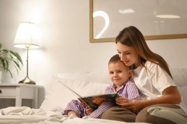 Anne gece yatak odasında oğluna masal okuyor.