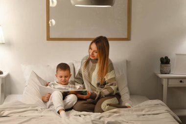 Anne gece yatak odasında oğluna masal okuyor.