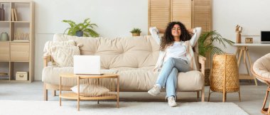 Genç Afro-Amerikalı kadın evdeki kanepede dinleniyor.