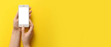 Sarı zemin üzerinde cep telefonu tutan kadın elleri metin için boşluk bırakıyor