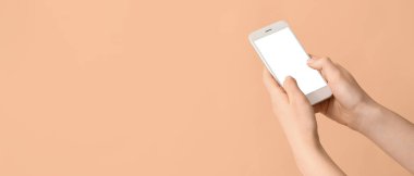 Bej arkaplan üzerinde cep telefonu tutan kadın elleri metin için yer var