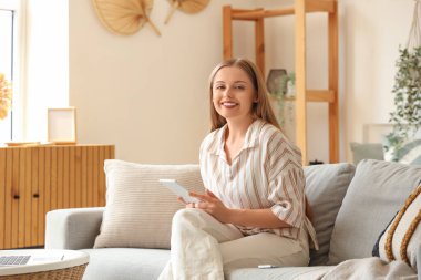 Evde tablet bilgisayarla çalışan genç bir kadın.