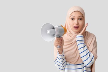 Gri arka planda megafonla genç Asyalı Müslüman kadını şok etti. Ulusal Duyulma Günü