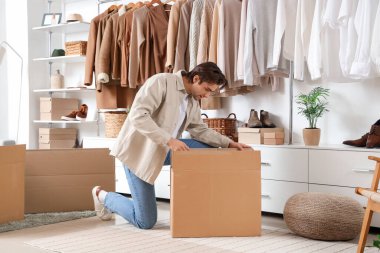 Soyunma odasında kostüm kutuları ve şık giysileri olan yakışıklı bir genç.