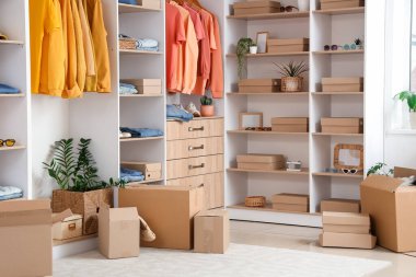 Modern giyinme odasının içinde gardırop kutuları, şık kıyafetler ve aksesuarlar var.