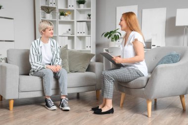 Kadın psikolog ofiste genç bir kızla konuşuyor.