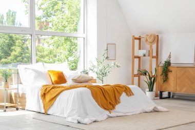 Büyük pencerenin yanında rahat yataklı, aydınlık yatak odasının içi.