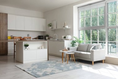 Modern bir stüdyo daire mutfak tezgahı, şık bir kanepe ve pencere kenarındaki masa.