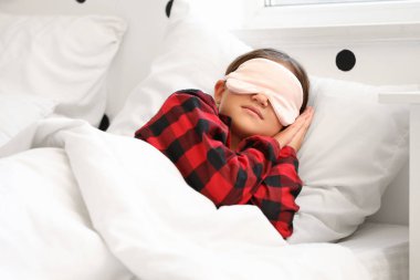 Maskeli, kareli pijamalı, tatlı küçük kız evde uyuyor.