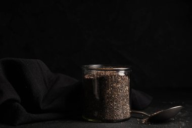Kavanoz ve kaşık siyah zemin üzerinde chia tohumları