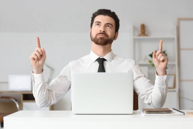 Genç işadamı ofisteki bir şeyi işaret ediyor.