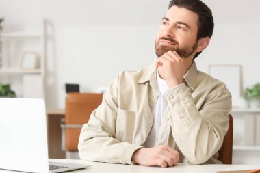 Genç adam ofisteki masaya bakıyor.