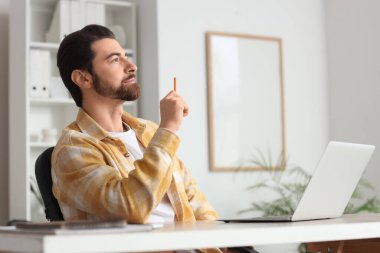 Yakışıklı adam ofisteki masaya doğru bakıyor.