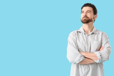 Yakışıklı adam mavi arka planda yukarı bakıyor.