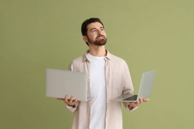 Laptopları olan yakışıklı bir adam yeşil arka planda yukarı bakıyor.