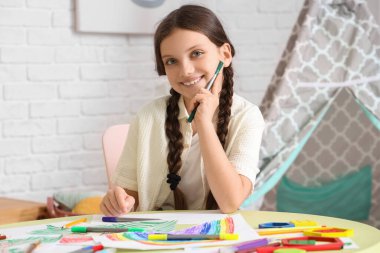 Evdeki masada güzel bir kız resmi çiziyor.