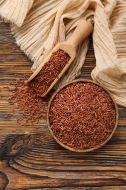 Ahşap zemin üzerinde çiğ kahverengi pirinç ile kase ve kepçe