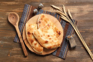 Ahşap zemin üzerinde lezzetli lavaş ve buğday dikenli tahta parçaları olan tahta.